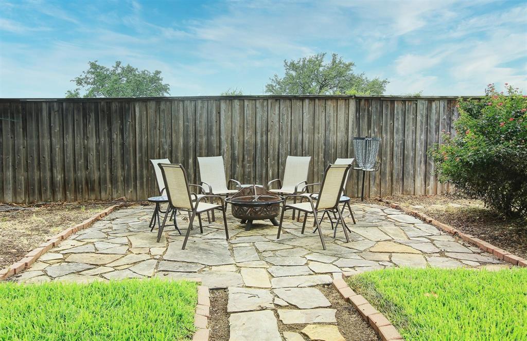 Beautifully designed backyard retreat with a firepit on inlaid flagstone, perfect for relaxing and entertaining.