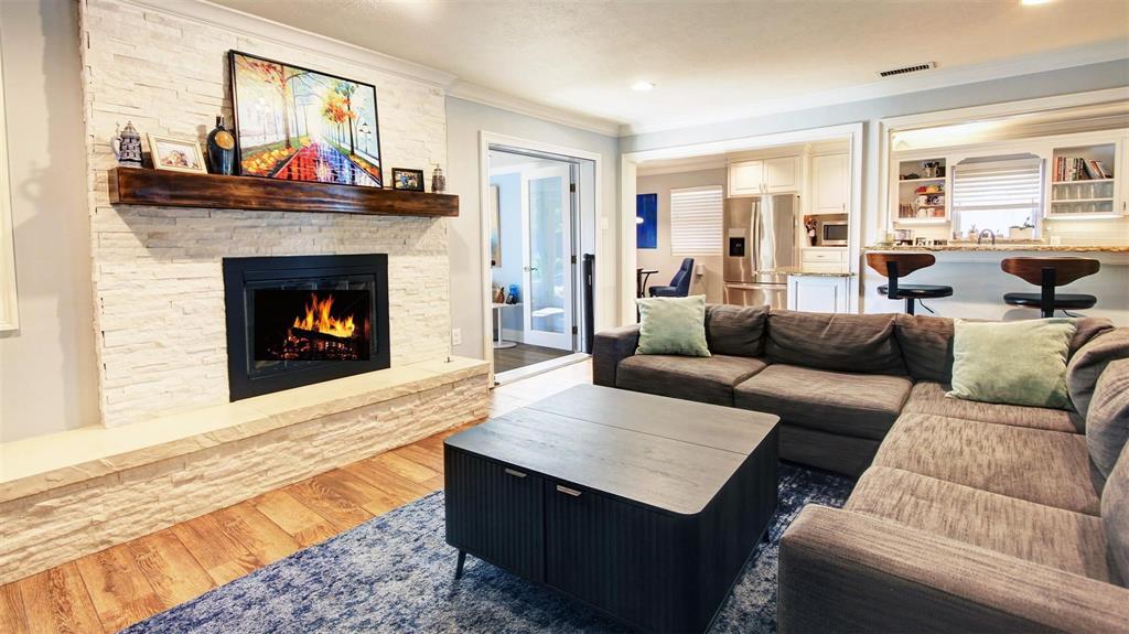 Spacious living room boasts a decorative gas fireplace with a beautiful wood mantel and raised extended hearth. Recessed lighting, and ceramic wood look tile floor. The open layout provides views of the kitchen, sunroom and dining areas. Love the stacked stone fireplace with additional seating.