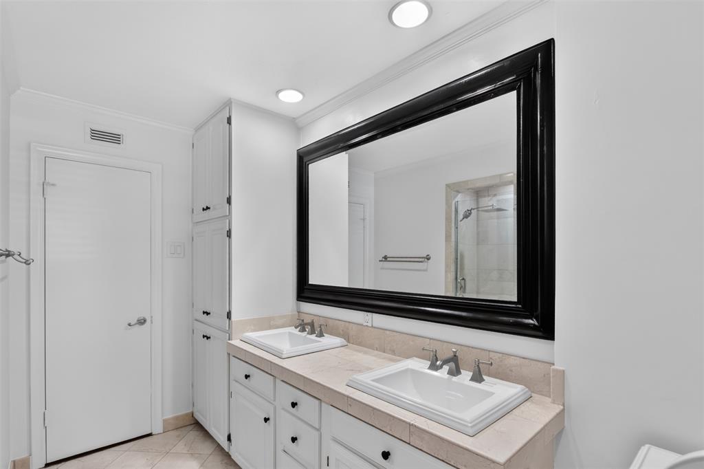 Another view of Primary bath with dual sinks, oversize framed mirror, recessed lights. Floor to ceiling cabinets allow for storage of linens, towels and additional toiletries.  Freshly painted August 2026