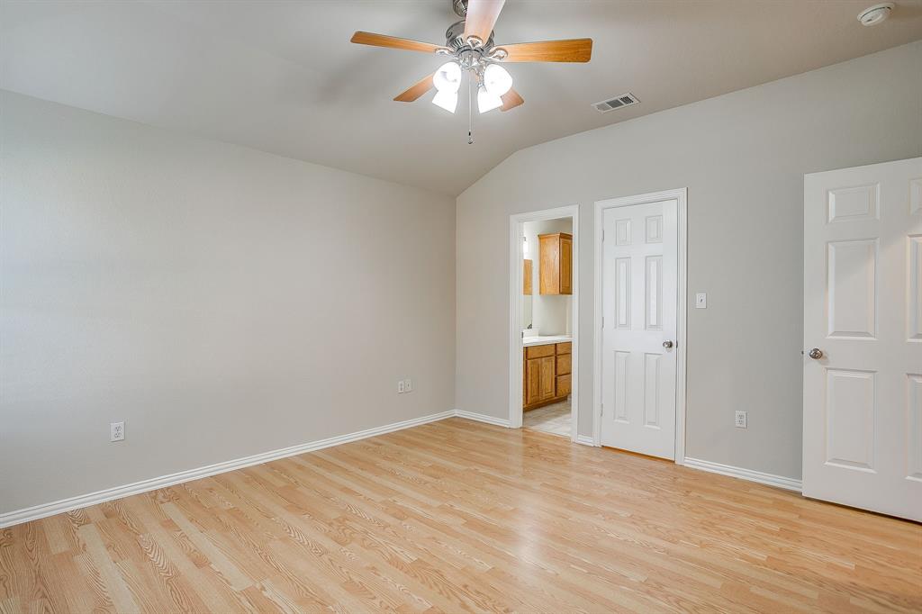 Vaulted ceiling featuring a ceiling fan with integrated lighting, wood-finish flooring, and six-panel interior doors