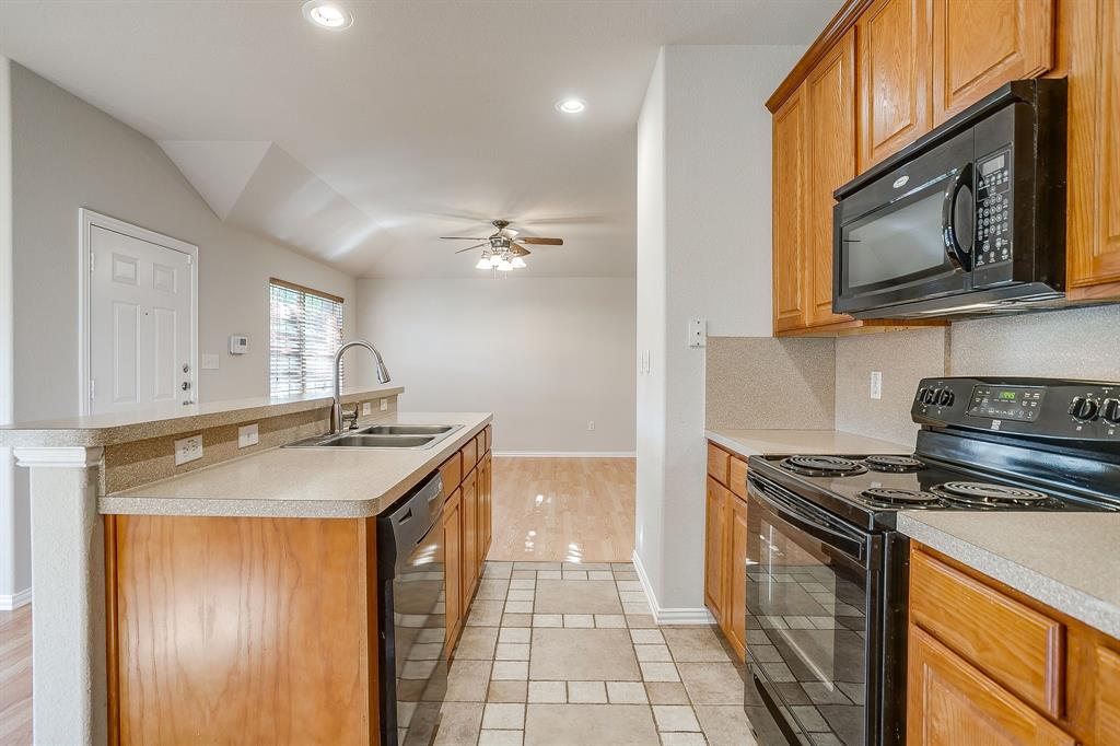 Kitchen featuring wood cabinetry, solid-surface countertops, recessed lighting, and a ceramic tile floor