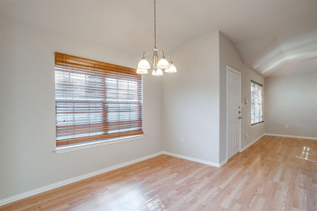 Interior space featuring wood-finish flooring, vaulted ceilings, multi-light chandelier, and large windows with horizontal blinds