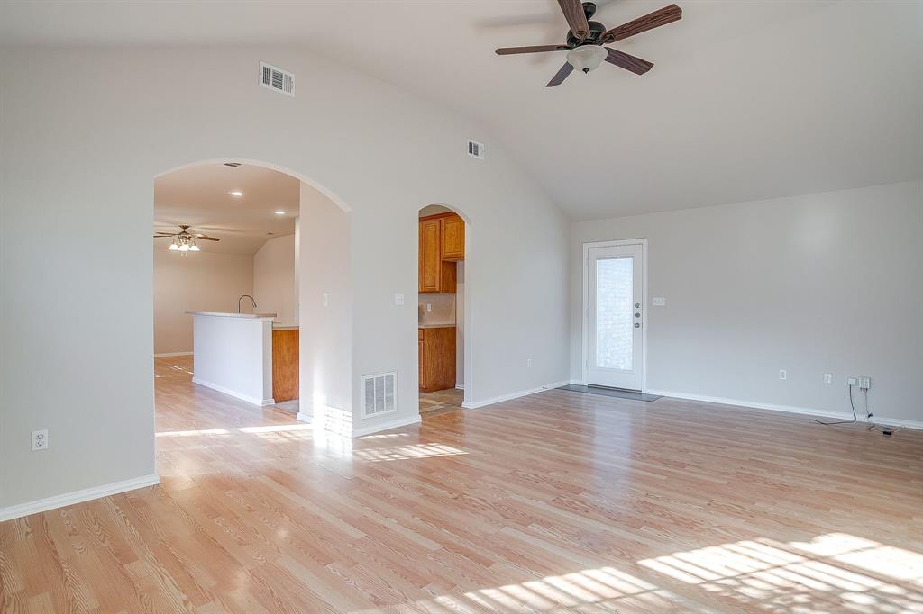 Vaulted ceilings, wood-finish flooring, architectural arched doorways, and a ceiling fan