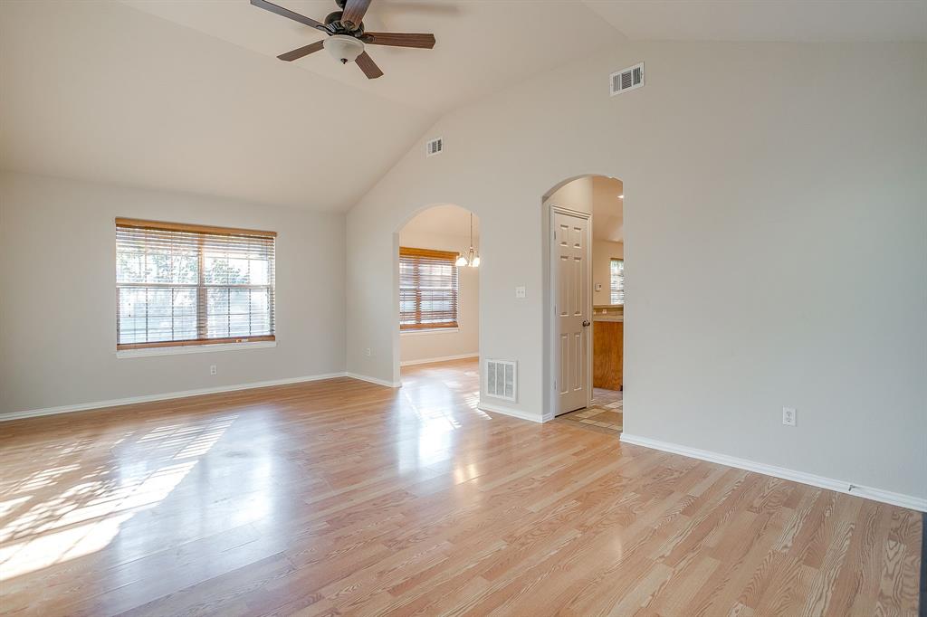Vaulted ceilings, wood-finish flooring, arched doorways, and a ceiling fan