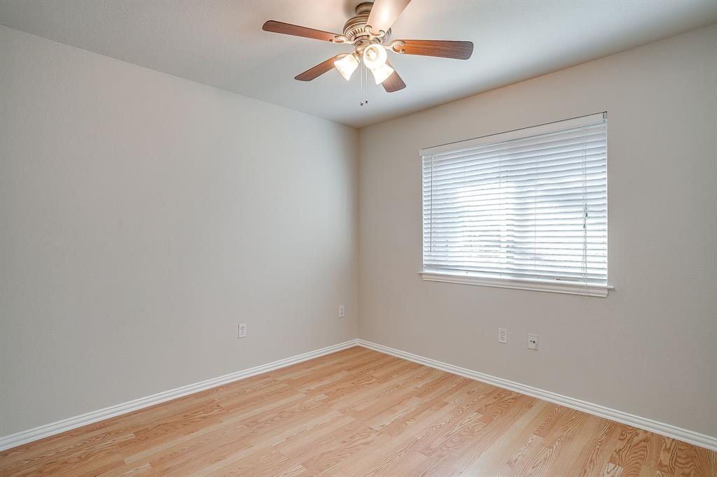 Interior room featuring wood-finish flooring, neutral wall paint, and a ceiling-mounted light fixture with a fan