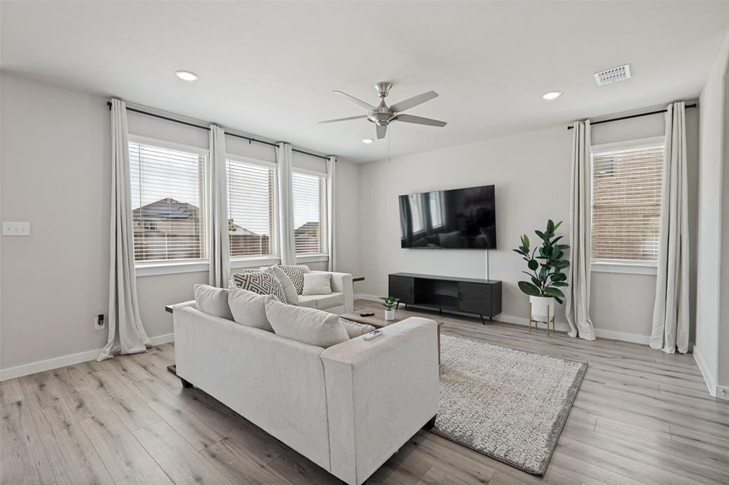 Wood-finish flooring, recessed lighting, ceiling fan, and large windows with horizontal blinds Wood-finish flooring, recessed lighting, ceiling fan, and large windows with horizontal blinds