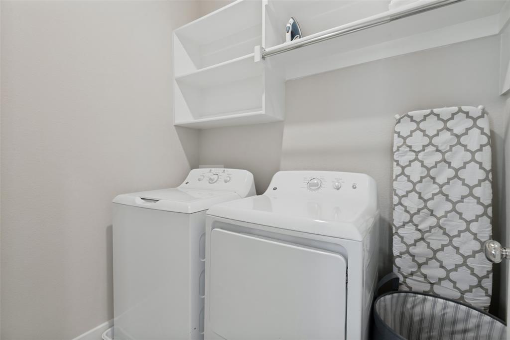 Laundry area featuring built-in white shelving, an integrated hanging rod, and neutral wall tones