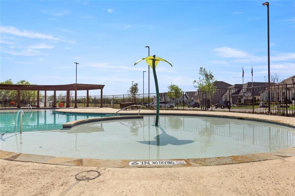Swimming pool featuring a shallow-depth entry area, a central water feature, stone coping, and a detached wooden pergola