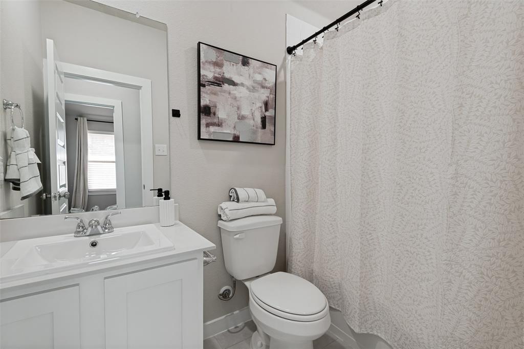 Bathroom featuring a white vanity cabinet with a rectangular basin, chrome dual-handle faucet, integrated countertop, and an expansive wall-mounted mirror