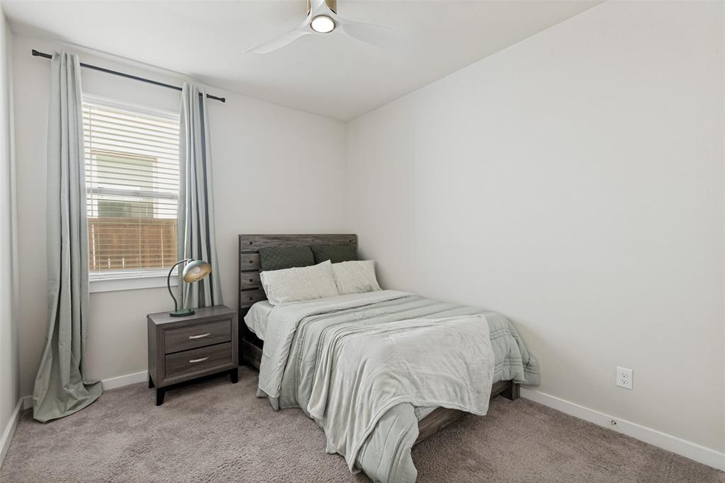 Neutral-toned interior featuring wall-to-wall carpeting, window with horizontal blinds, and a ceiling-mounted light fixture with fan blades