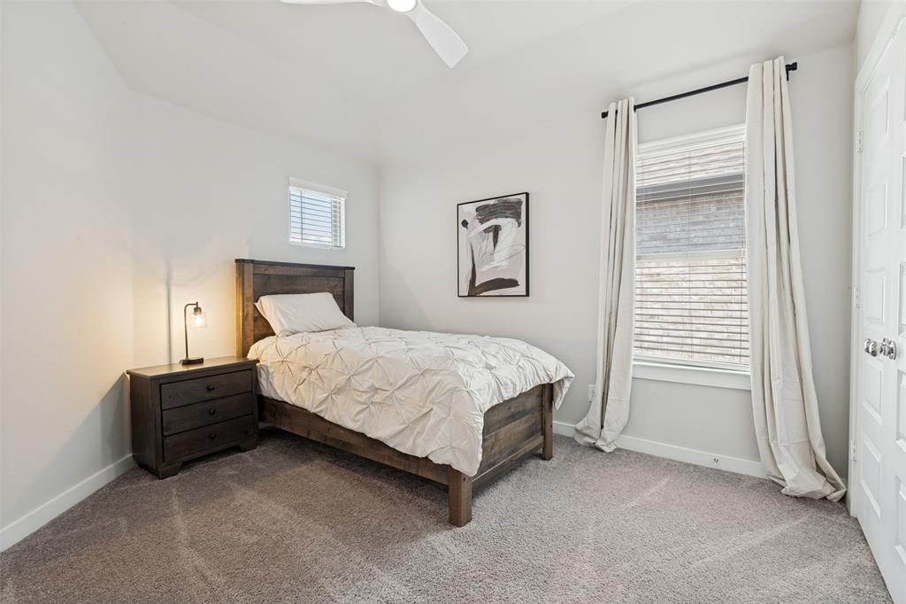Neutral-toned room featuring neutral carpeting, multi-pane window with horizontal blinds, overhead ceiling fan with light, and a multi-panel interior door