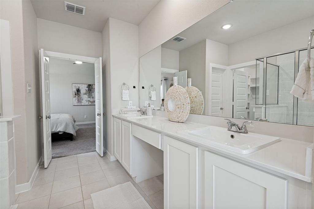 Double vanity featuring white cabinetry, a solid-surface countertop, dual drop-in sinks, and a full-width wall mirror