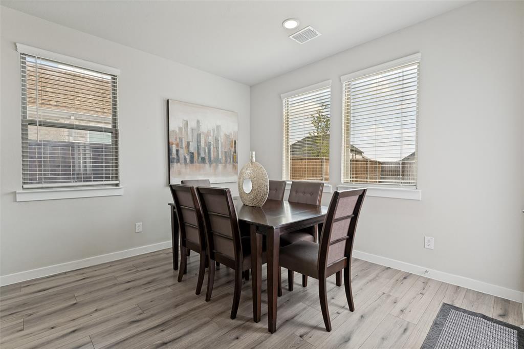 Neutral-toned interior space featuring wood-finish flooring, three windows with horizontal blinds, and recessed ceiling lighting Neutral-toned interior space featuring wood-finish flooring, three windows with horizontal blinds, and recessed ceiling lighting