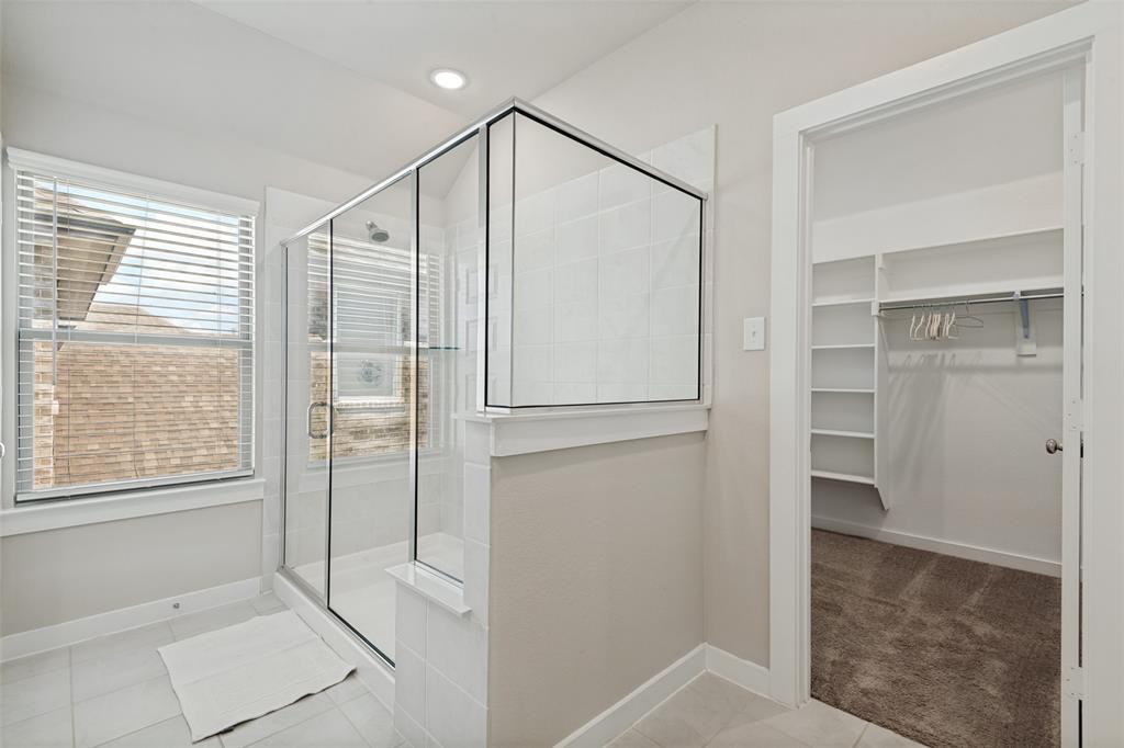 Walk-in shower with a glass enclosure, tile surround, recessed lighting, and a walk-in closet featuring built-in shelving