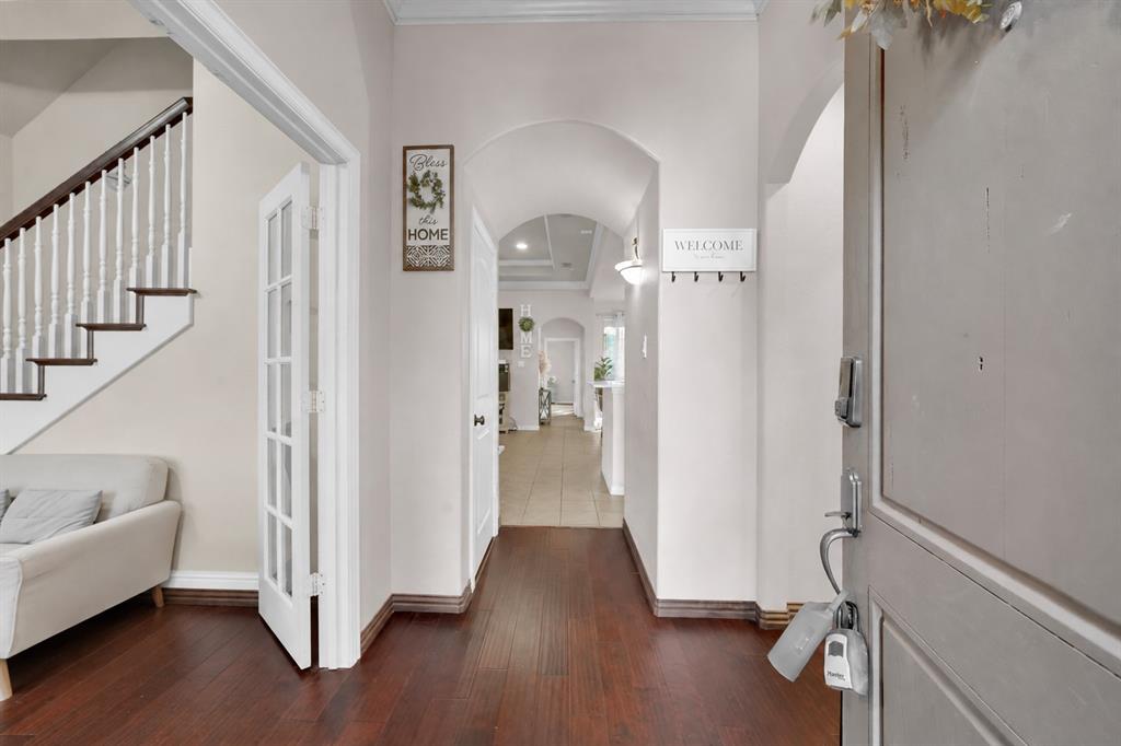 Entryway featuring wood-finish flooring, a staircase with a white spindle railing, and an arched hallway passage