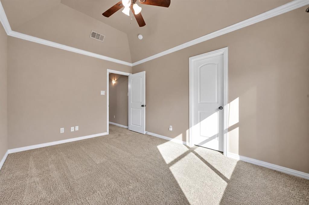 Vaulted ceiling featuring crown molding, neutral carpeting, and a central ceiling fan with integrated lighting