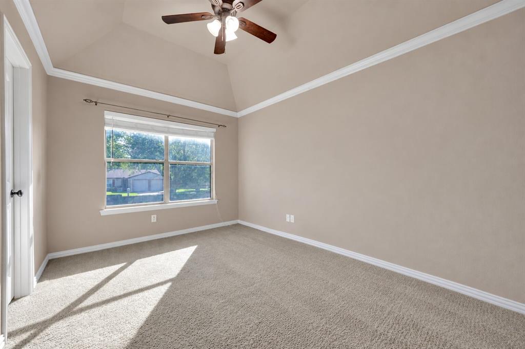 Tray ceiling featuring crown molding, neutral carpeting, and a multi-blade ceiling fan