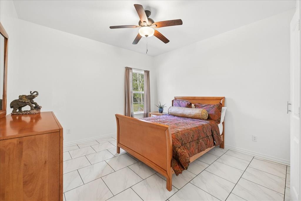 Light-filled room featuring large-format rectangular floor tile and a central ceiling fan with integrated lighting