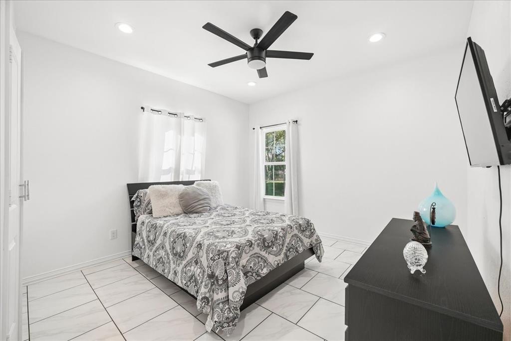 Large-format tile flooring, recessed ceiling lighting, and a multi-blade matte black ceiling fan