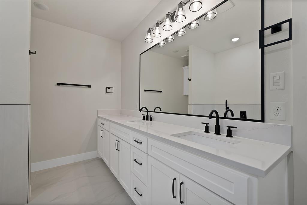 Double vanity featuring white cabinetry, quartz countertops, dual rectangular under-mount sinks, matte black widespread faucets, and a large mirror with a black frame
