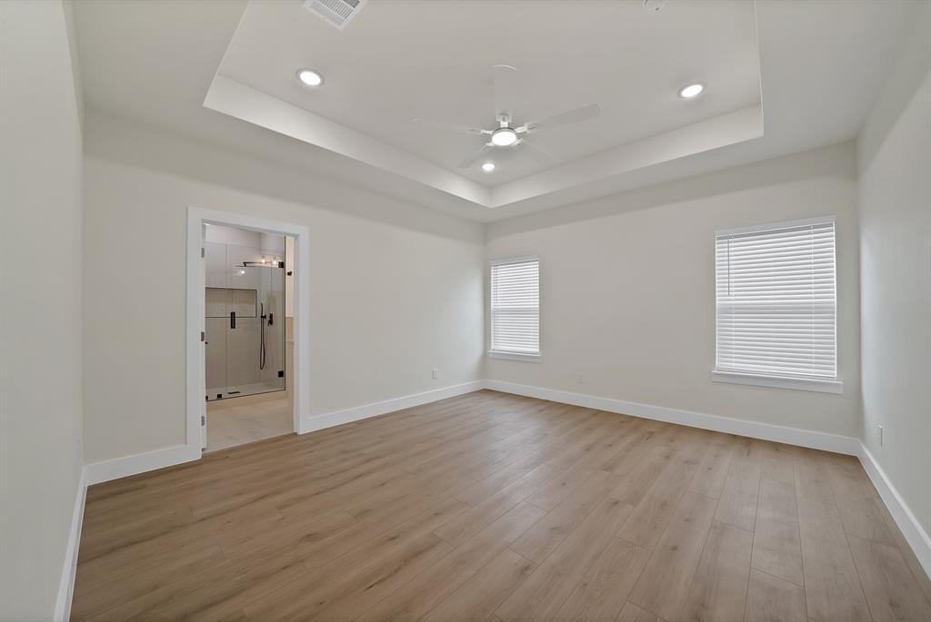 Room featuring a tray ceiling, wood-finish flooring, recessed lighting, and a ceiling fan with an integrated light fixture