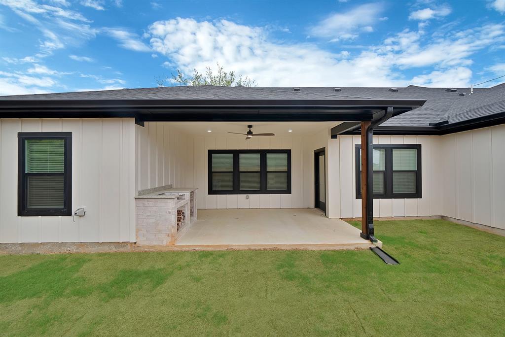 Covered patio featuring a built-in outdoor kitchen station, vertical board-and-batten siding, recessed lighting, and a ceiling fan