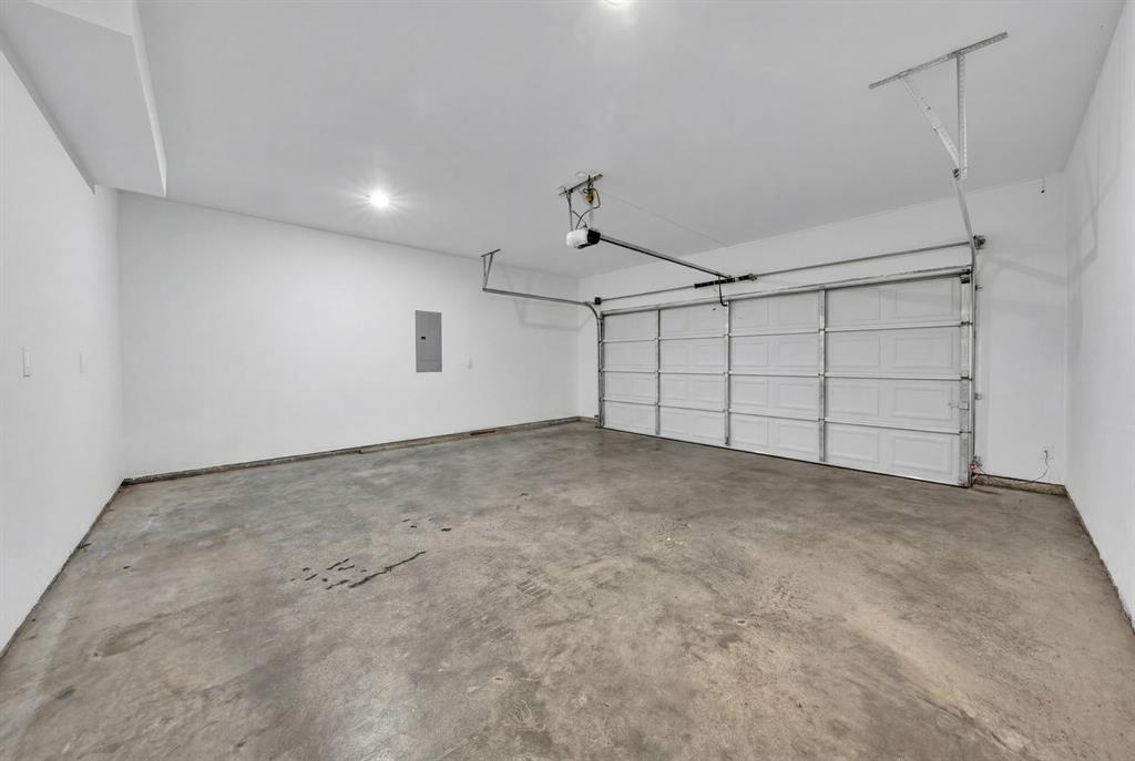 Attached two-car garage featuring a sectional door, concrete flooring, recessed lighting, and an automated opener