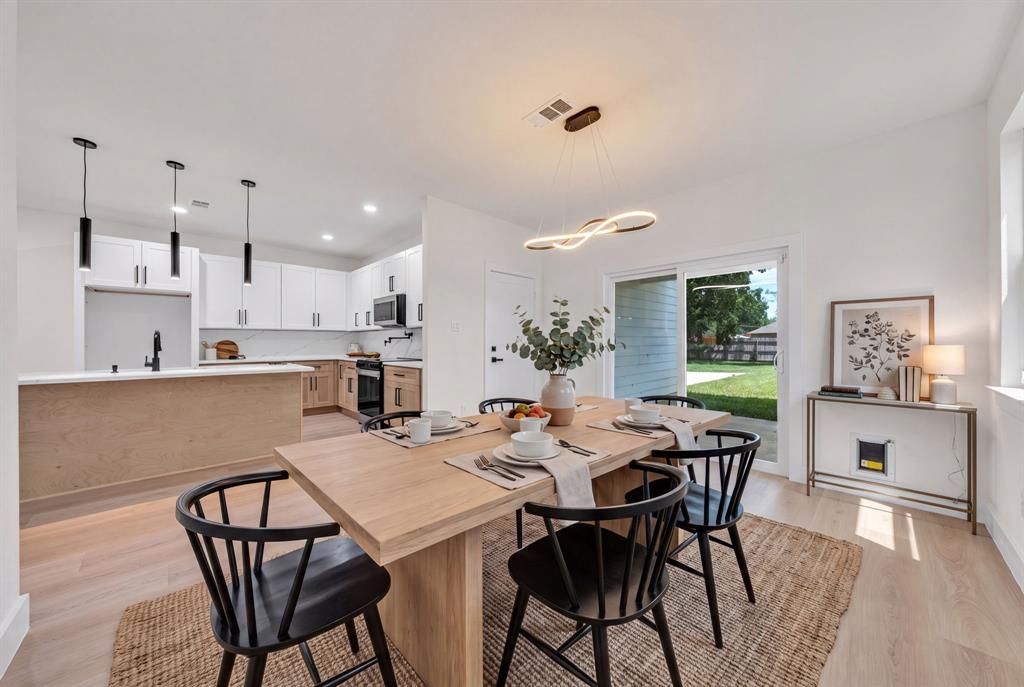 Kitchen featuring white upper cabinetry, light wood-finish lower cabinetry, stone-look countertops, matte black plumbing fixtures, and wood-finish flooring throughout Kitchen featuring white upper cabinetry, light wood-finish lower cabinetry, stone-look countertops, matte black plumbing fixtures, and wood-finish flooring throughout