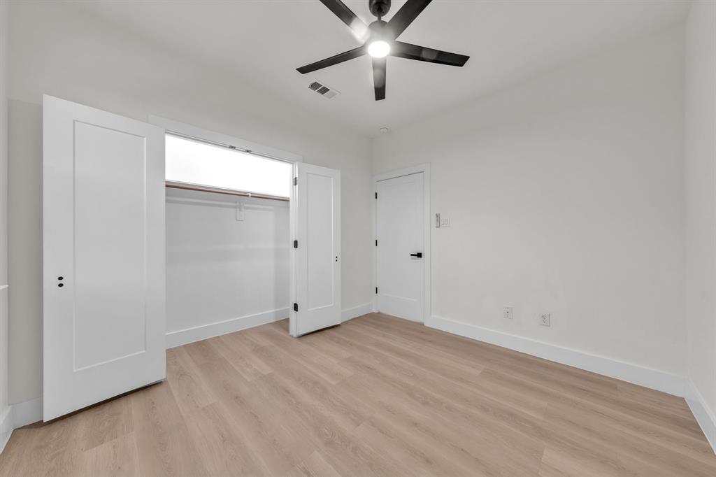 Wood-finish flooring, matte black ceiling fan with integrated lighting, shaker-style interior doors with matte black hardware, and double-door closet