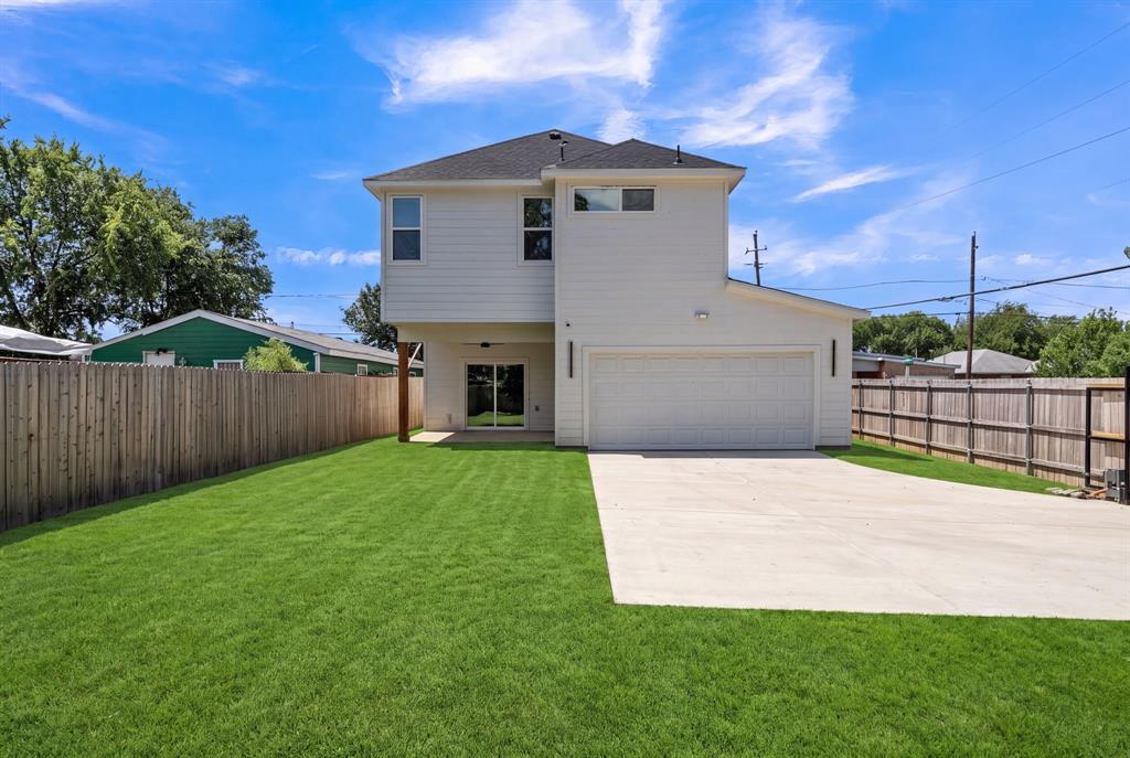 Two-story exterior featuring white siding, a multi-car garage, an expansive lawn, and wood-paneled privacy fencing