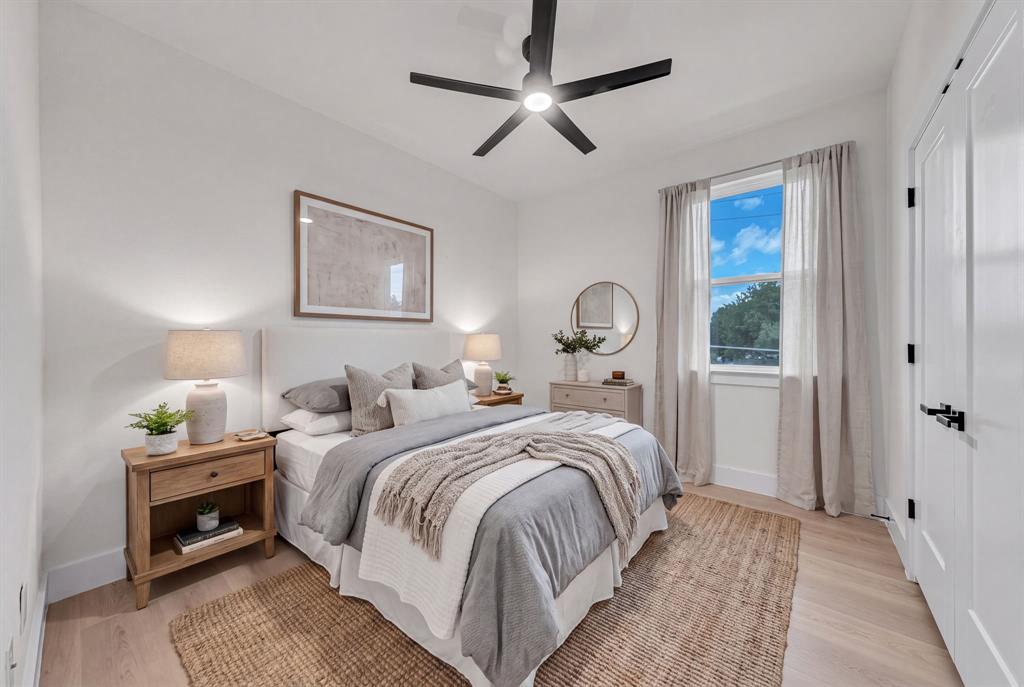 Neutral-toned interior featuring wood-finish flooring, a matte black multi-blade ceiling fan, and a single-hung window with black hardware accents