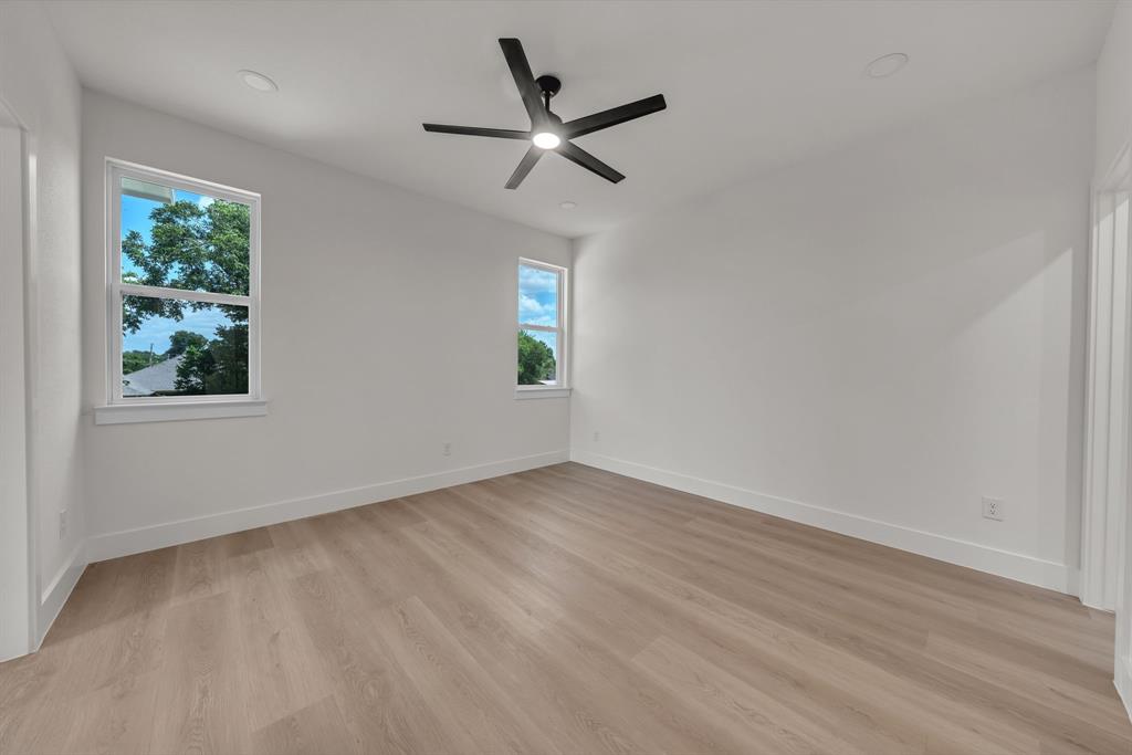 Neutral interior featuring wood-finish flooring, recessed lighting, double-pane windows, and a matte black ceiling fan