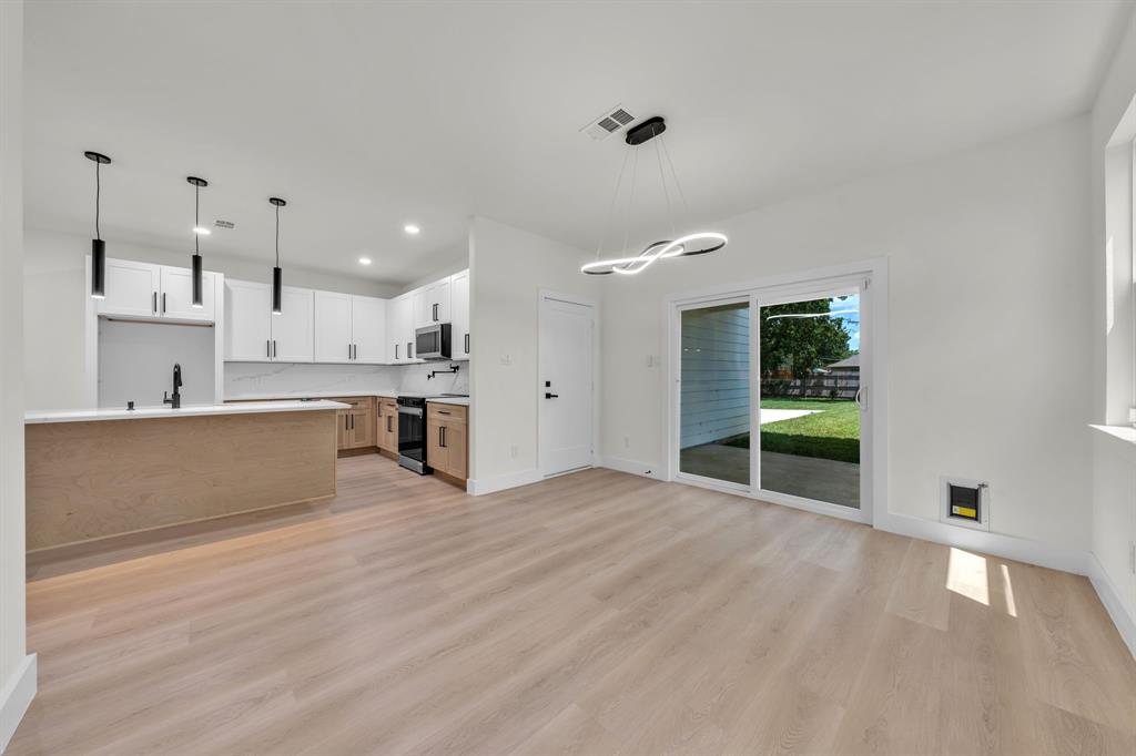 Kitchen featuring white upper cabinetry, wood-finish lower cabinetry, quartz countertops with a stone backsplash, matte black hardware, and wood-finish flooring Kitchen featuring white upper cabinetry, wood-finish lower cabinetry, quartz countertops with a stone backsplash, matte black hardware, and wood-finish flooring