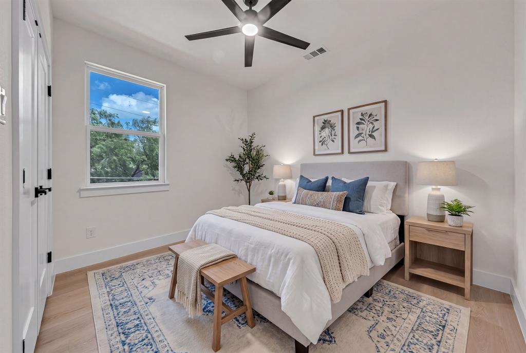 Neutral-toned room featuring wood-finish flooring, a contemporary matte black ceiling fan, and double closet doors with matching black hardware
