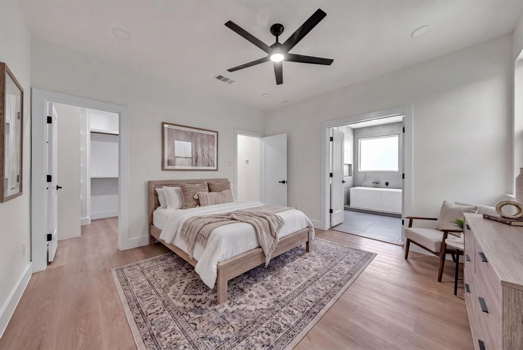 Neutral-toned bedroom featuring wood-finish flooring, a matte black multi-blade ceiling fan, recessed lighting, and a walk-in closet
