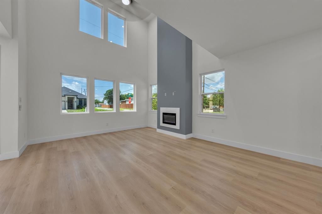 Two-story vaulted ceiling, wood-finish flooring, multi-pane windows, and a gas fireplace with a floor-to-ceiling surround