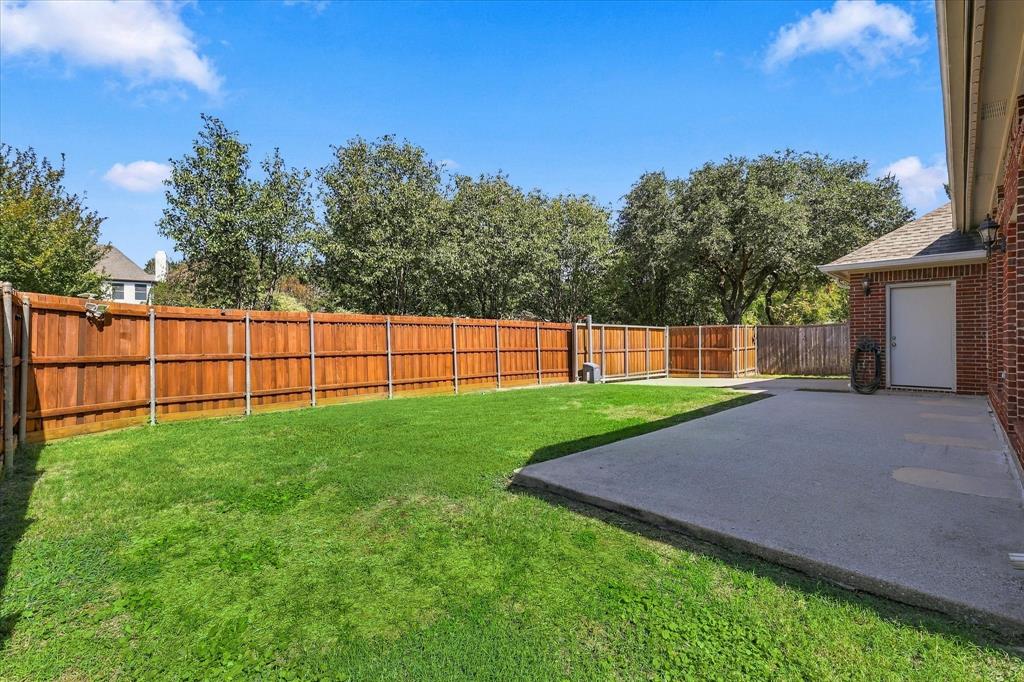 Fenced backyard featuring a manicured lawn and concrete patio.