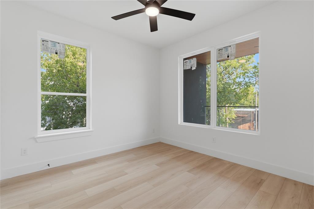 Room featuring light wood-finish flooring, dual-pane windows, and a ceiling-mounted light fixture with fan blades