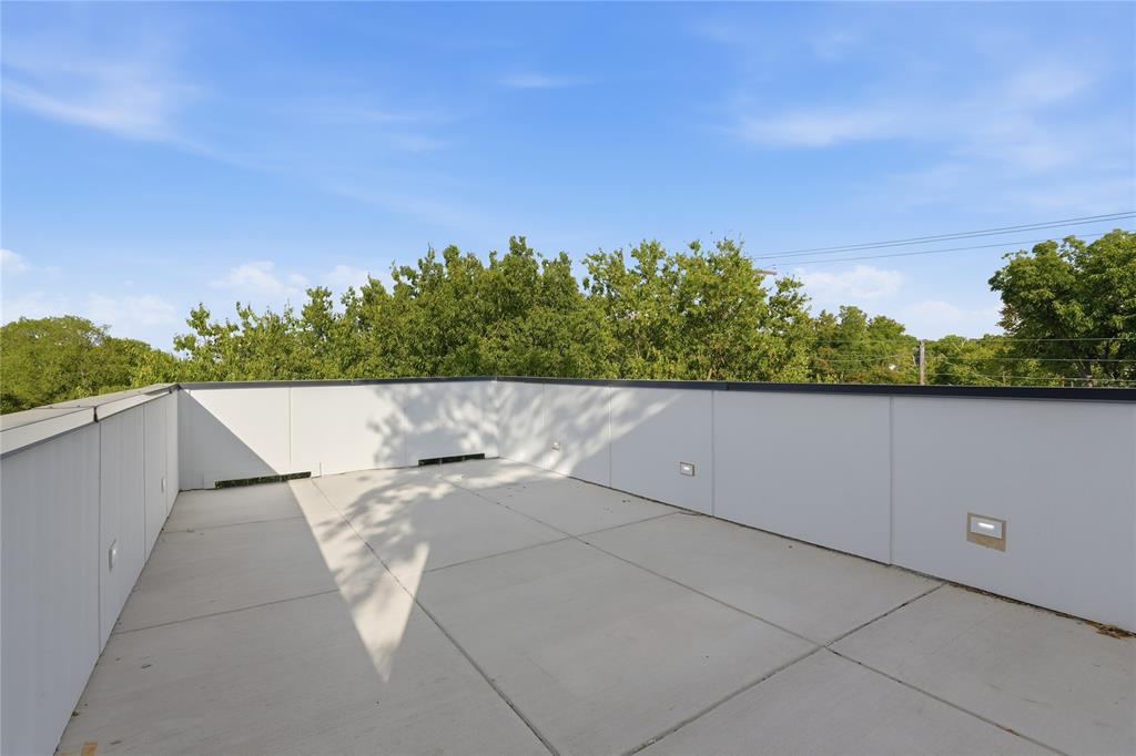 Rooftop terrace featuring concrete flooring, white paneled perimeter walls, and built-in recessed lighting