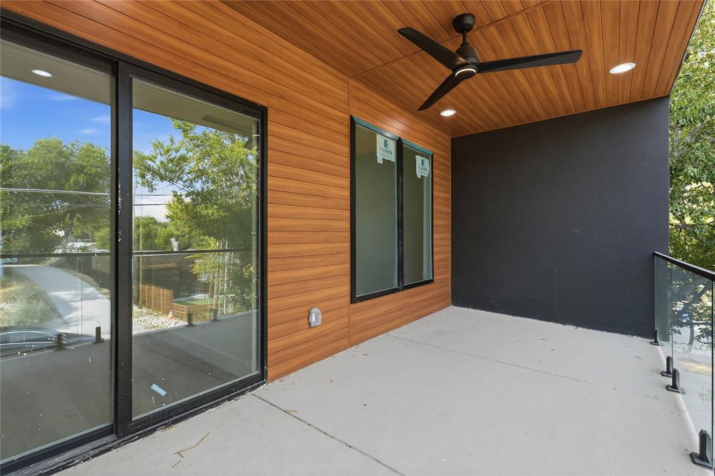 Covered balcony featuring wood-finish paneling, a ceiling-mounted fan, recessed lighting, and a glass panel railing
