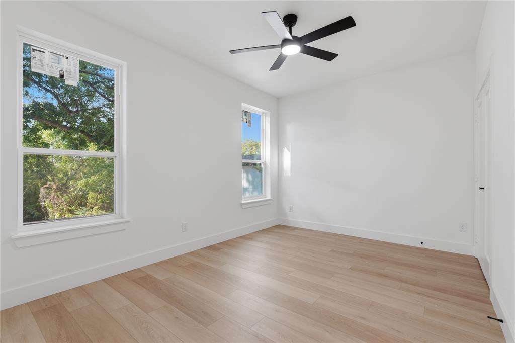 Double-height living area featuring a floor-to-ceiling dark textured fireplace surround with a linear electric insert, wood-finish flooring, recessed lighting, and a glass-paneled mezzanine railing