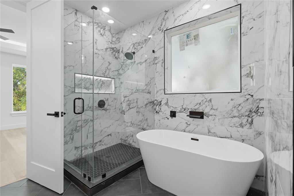 Walk-in shower featuring a frameless glass enclosure, recessed wall niche, and hex-tile flooring