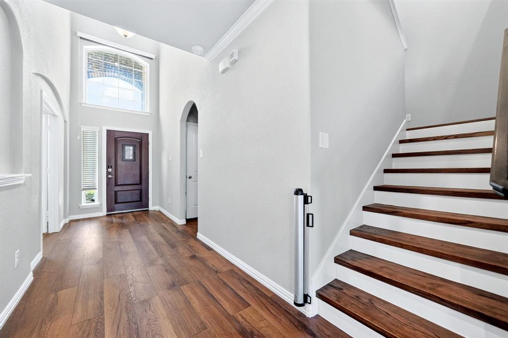 Foyer featuring high ceilings, wood-finish flooring, an arched doorway, a transom window, and a staircase with wood treads
