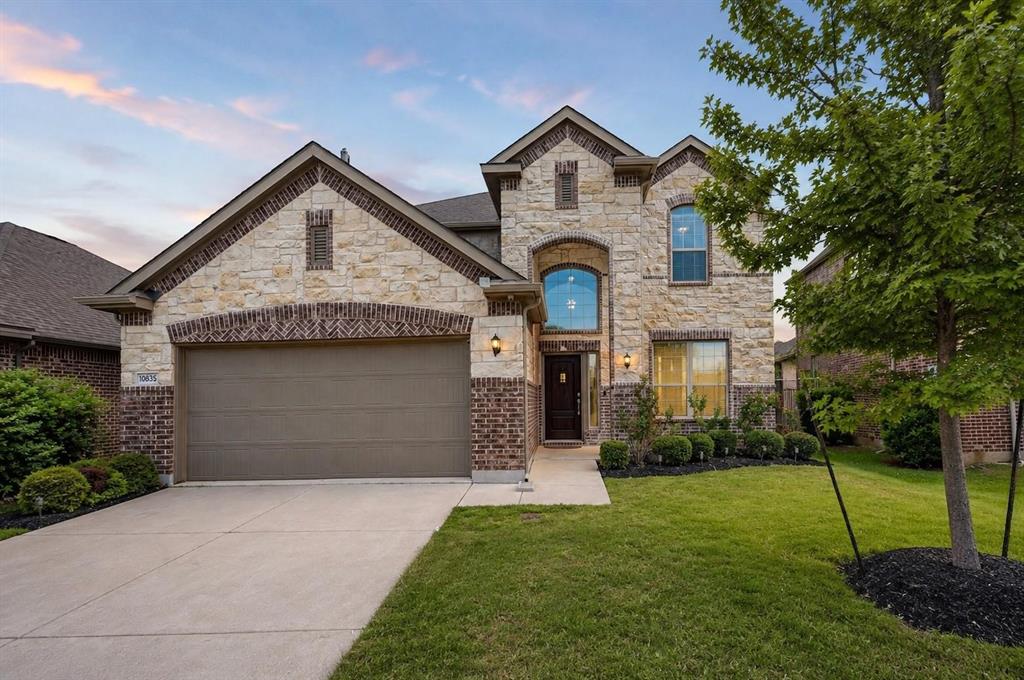Multi-story exterior featuring a stone and brick facade, arched window detailing, covered entryway, and an attached two-car garage Multi-story exterior featuring a stone and brick facade, arched window detailing, covered entryway, and an attached two-car garage