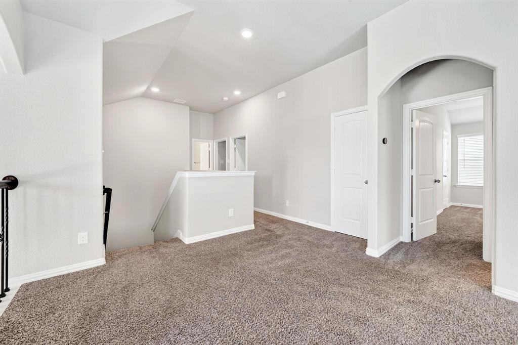 Vaulted ceiling with recessed lighting, neutral wall palette, carpeted flooring, and an arched entry