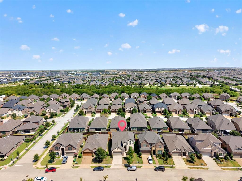 Aerial perspective of residential property featuring a multi-gabled roofline, brick and stone veneer exterior, attached two-car garage, and concrete driveway