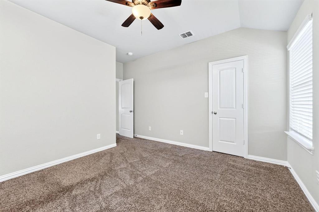Vaulted ceiling featuring a ceiling fan with integrated lighting, neutral wall paint, carpeted flooring, and a multi-panel interior door