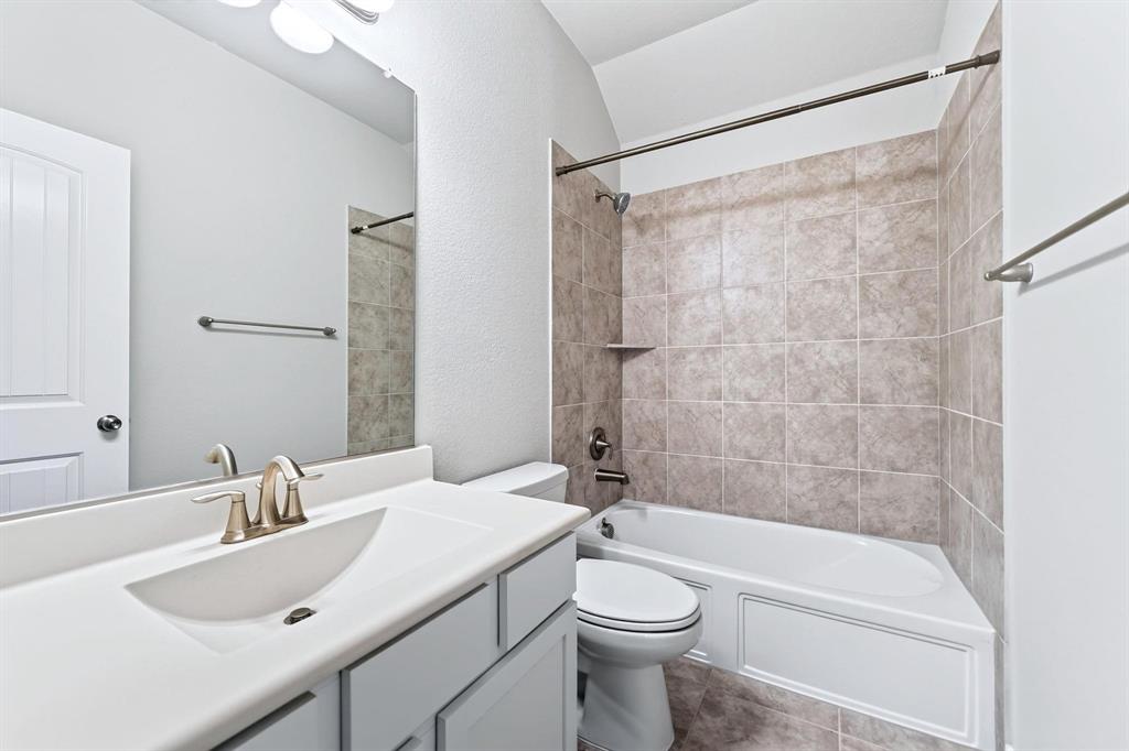Bathroom featuring a vanity with an integrated sink, brushed-finish faucet, large mirror, and a tub-shower combination with ceramic tile surround