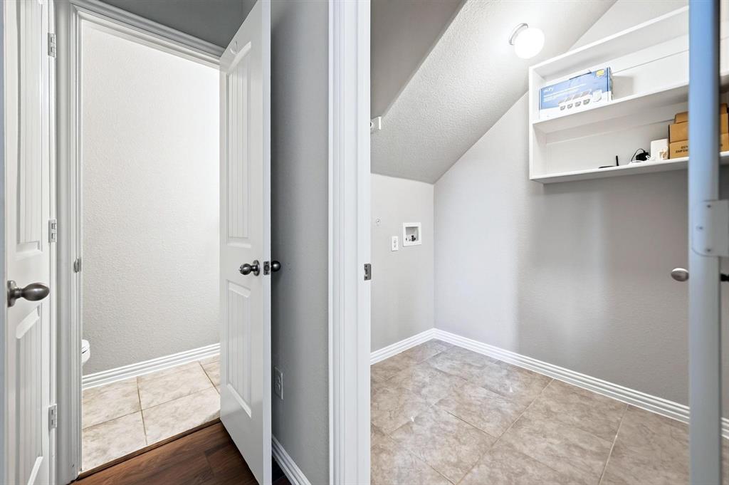 Utility room featuring tile flooring, built-in shelving, and washer-dryer hookups