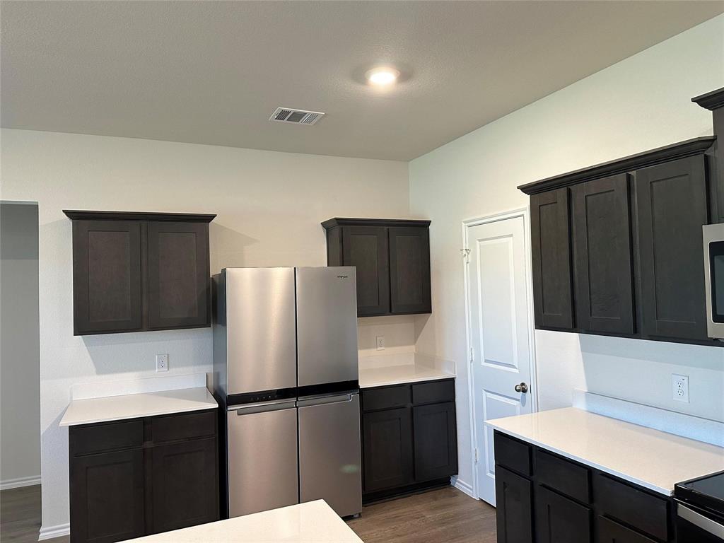 Kitchen featuring appliances with stainless steel finishes, dark wood-style floors, and light stone countertops